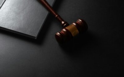 Wooden judge gavel resting next to a closed law book