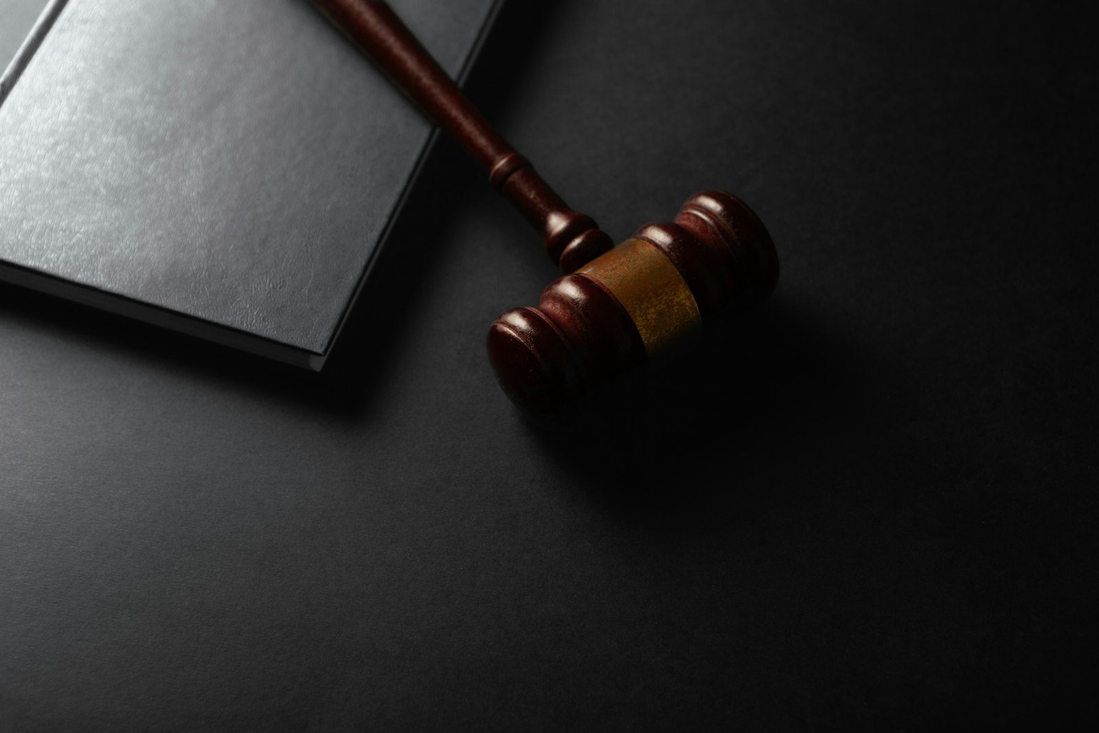 Wooden judge gavel resting next to a closed law book