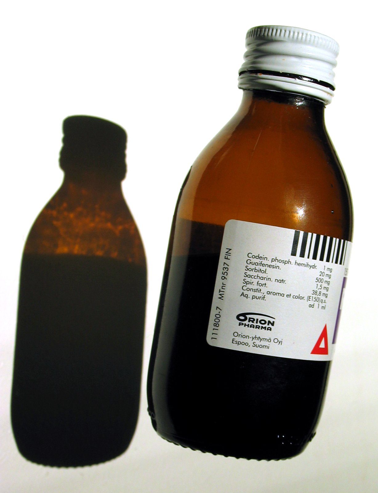 A bottle of cough syrup medicine with a dosage measuring cup