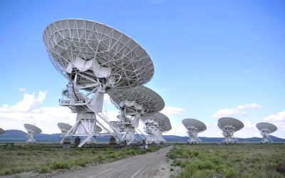 A dish-shaped radio telescope pointed at the night sky near the Milky Way
