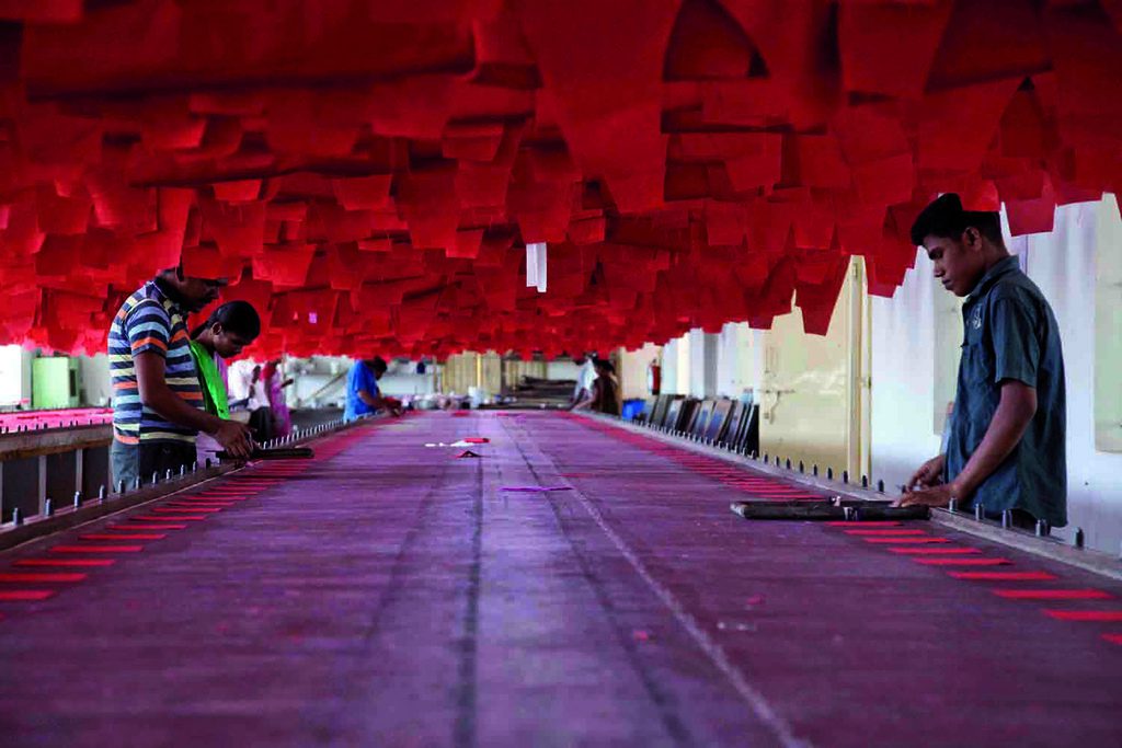 Workers at sewing machines on a textile factory floor in India