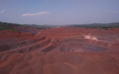 Open-cast iron ore mine with terraced benches and haul roads