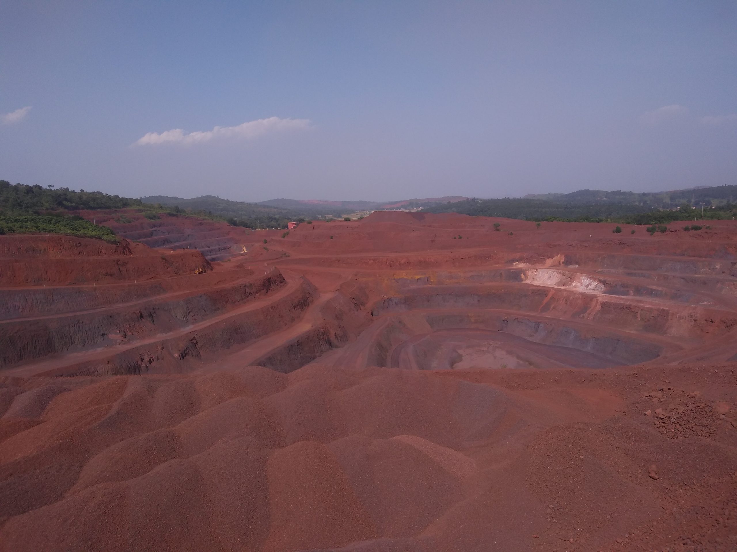 Open-cast iron ore mine with terraced benches and haul roads