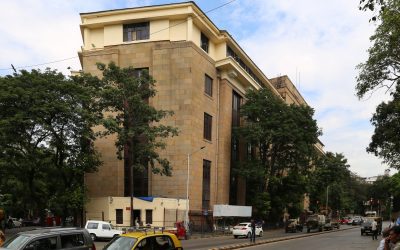 Street-level view of the Reserve Bank of India building in Mumbai with traffic passing in front