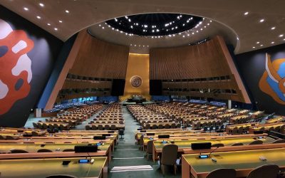 Interior of the United Nations General Assembly Hall in New York, showing the rostrum and rows of delegate desks