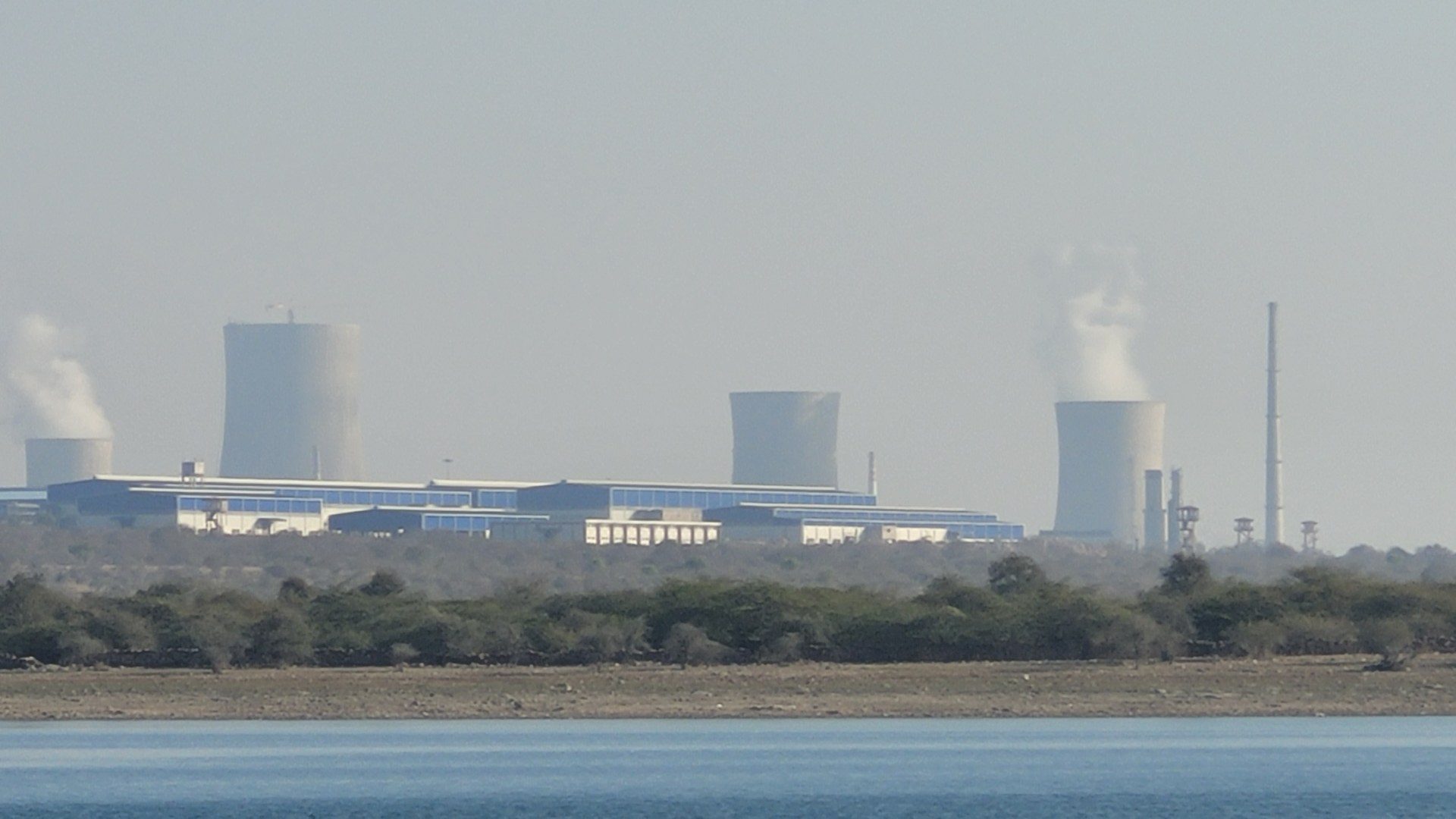 Cooling towers and reactor buildings of the nuclear power plant at Rawatbhata seen across a lake