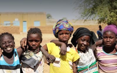 A group of smiling girls standing arm in arm outside a school building