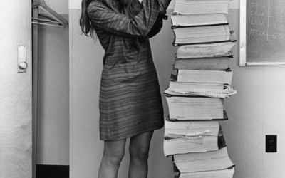 Margaret Hamilton in 1969 standing beside a tall stack of printed Apollo guidance software listings