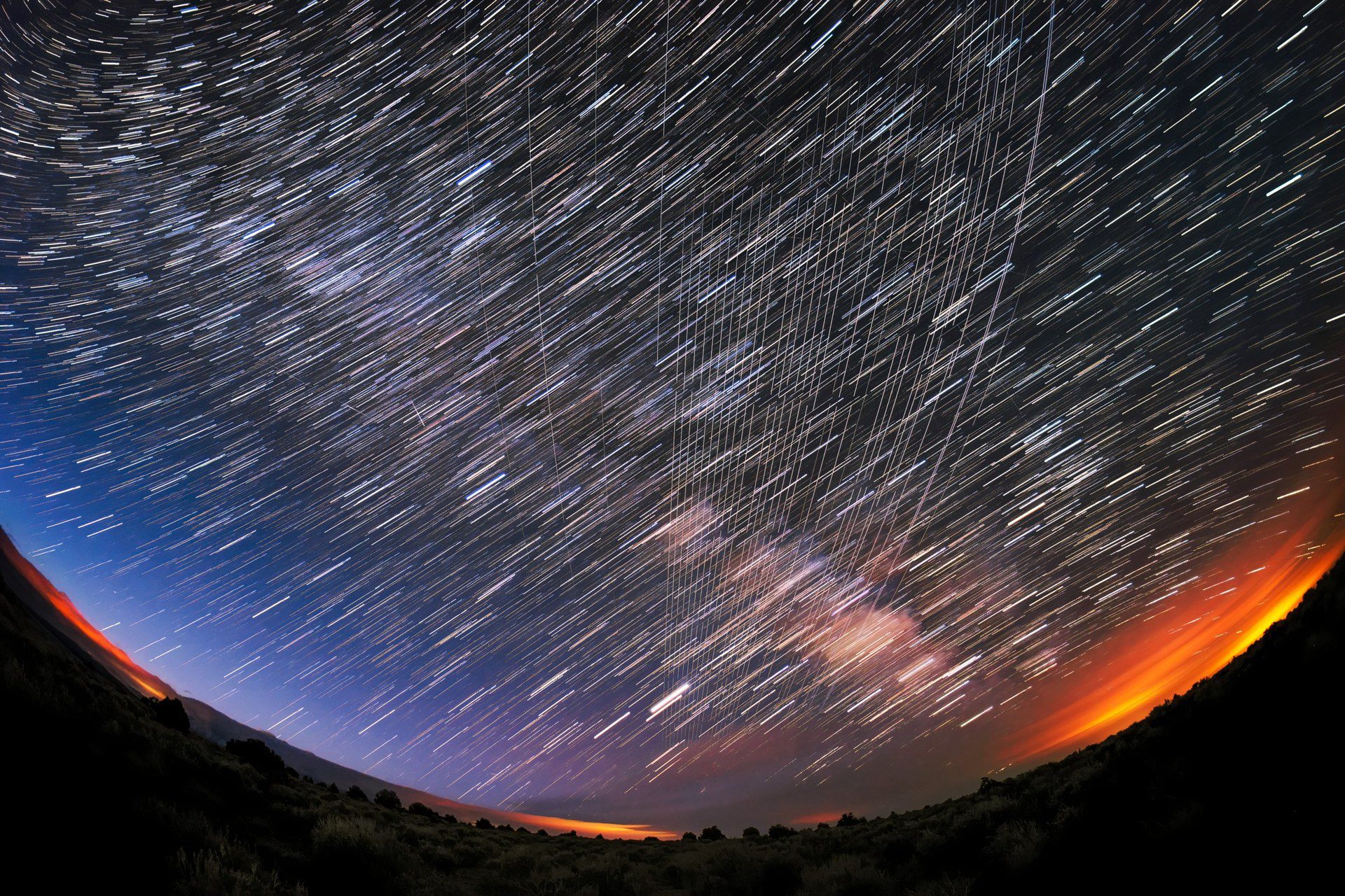 A line of satellites crossing the night sky above a forest soon after launch