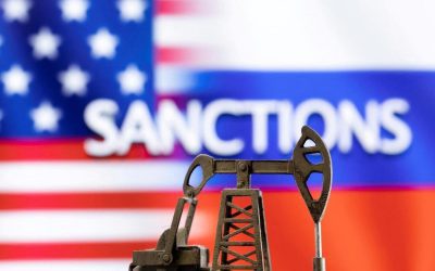 Model of an oil pump jack in front of the word sanctions and US and Russian flag colours, a photo illustration
