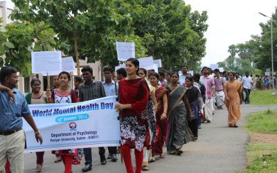 Students walking in a World Mental Health Day awareness rally holding a banner and placards